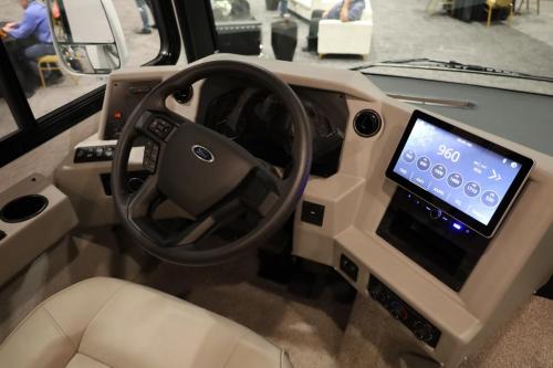 The driver’s area of the 2025 Newmar Bay Star Sport boasts a sleek steering wheel with logo, user-friendly controls, and a high-tech digital display, reflecting the motorhome’s luxurious and contemporary design.