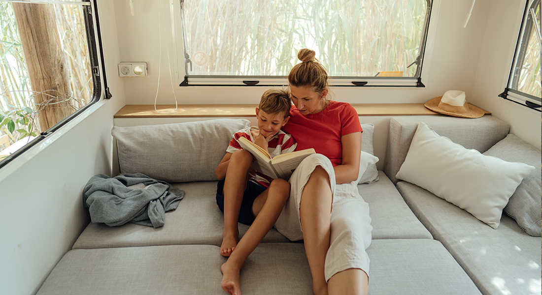 Mother and Son Reading Together in Lounge Bed of Class B Motorhome